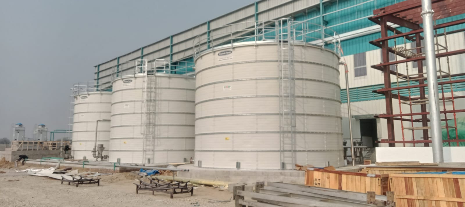 White Zinc Aluminium Steel tanks under installation near an industrial shed